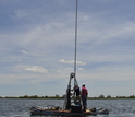 Scientists in a boat collecting a sediment core